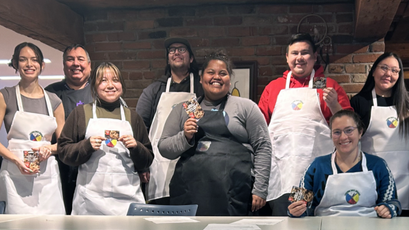 A group of students hold up small cards while wearing white aprons.