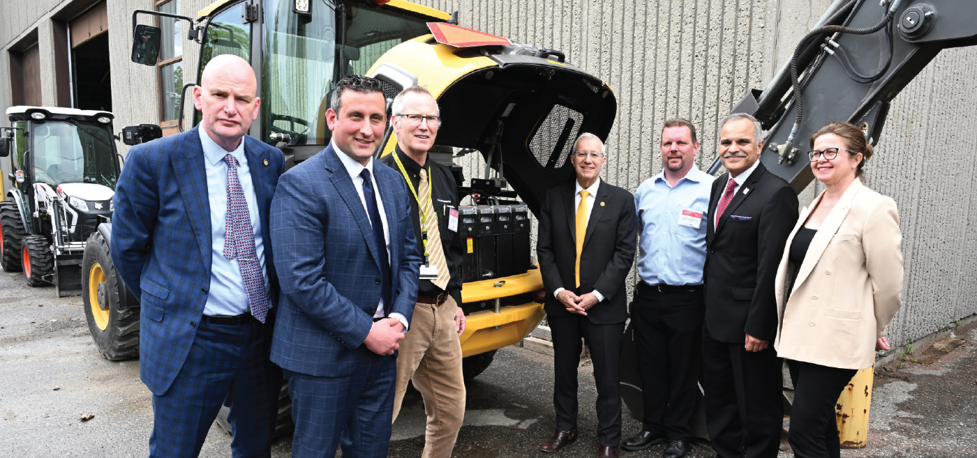 Group of people in front of construction vehicle.