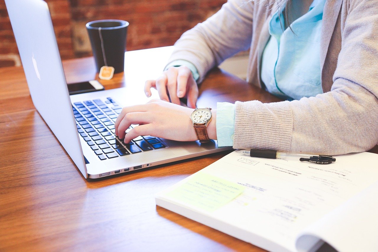 person sitting on a desk typing on a laptop