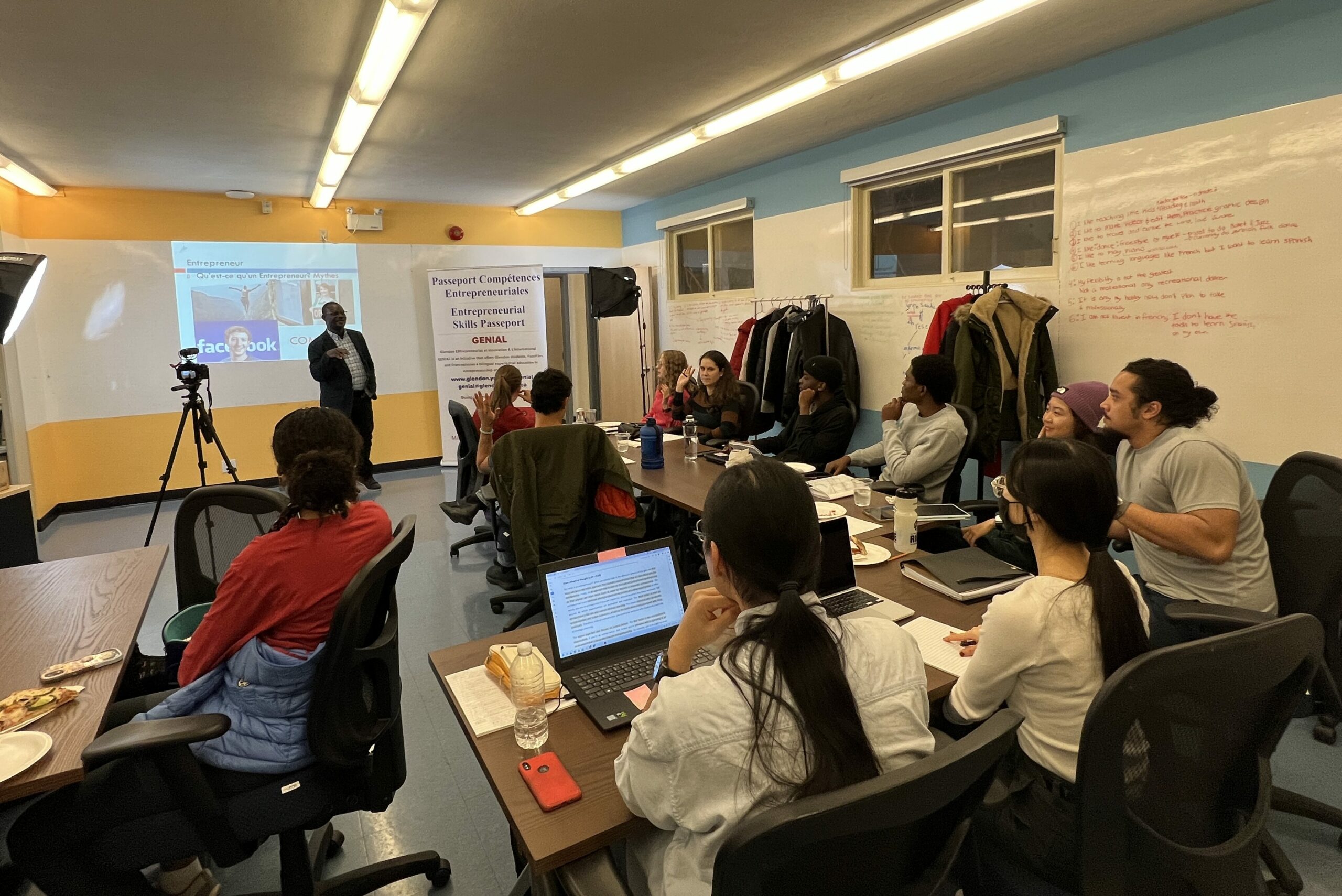 Un groupe diversifié d’étudiants assis à des pupitres dans une salle lumineuse et GENIAL lors d’une réunion.
