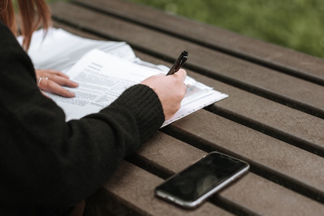 Woman taking notes in text near mobile phone