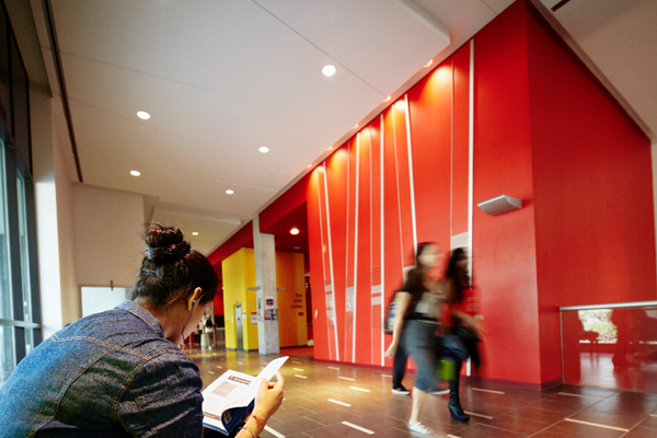 images of students walking in a hallway while another student is sitting down, reading