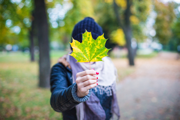 photo of a female holding a maple leaf in front of her face