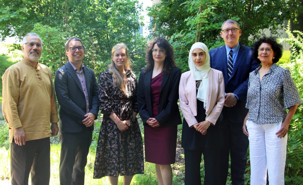 a photo of from left to right the names are as follows: Dr. Ali Asgary, Dr. Eric Kennedy, Dr. Jennifer Spinney (Area Coordinator), Dr. Evalyna Bogdan, Dr. Aaida Mamuji (Graduate Program Director), Dr. Jack Rozdilsky, Dr. Nirupama Agrawal