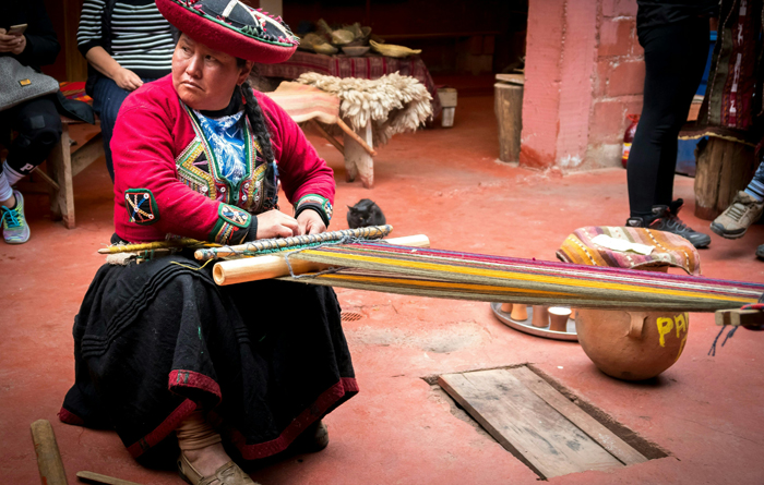 A Woman in Traditional Clothing Sitting and Weaving