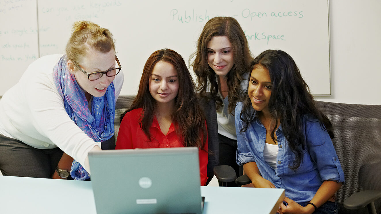 Group of four students looking at a laptop