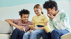 Photo of a diverse group of kids smiling and looking at a phone together