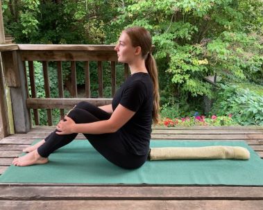 Woman is sitting on the yoga mat, bent knees and straight back