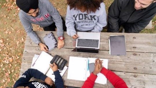 students sitting on the bench with their laptop and notes