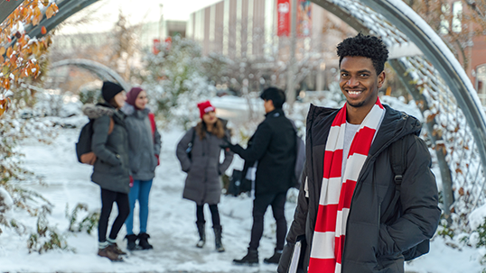 Students dressed in winter clothing stand outside on Keele campus