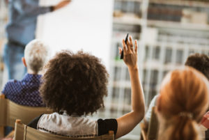 Black woman raising her hand to answer question in seminar