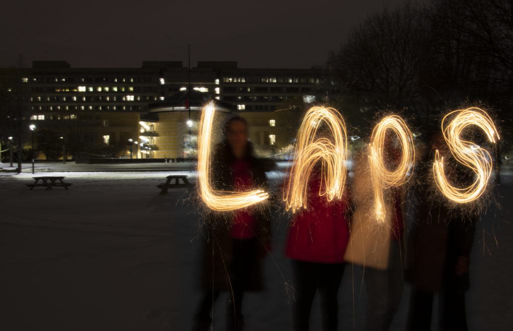 time laps photo at night of students writing "LAPS" with light source