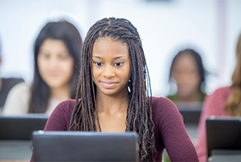 A multi-ethnic group of students are working on a project in the computer lab. 