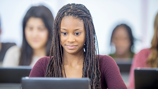 A multi-ethnic group of students are working on a project in the computer lab.