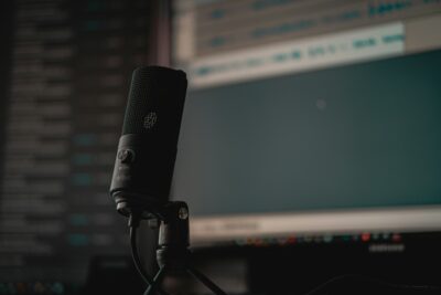 A photo of an up close all black microphone. The background is blurred and the focus is on the microphone. The photo is by Cedrik Wesche on Unsplash.