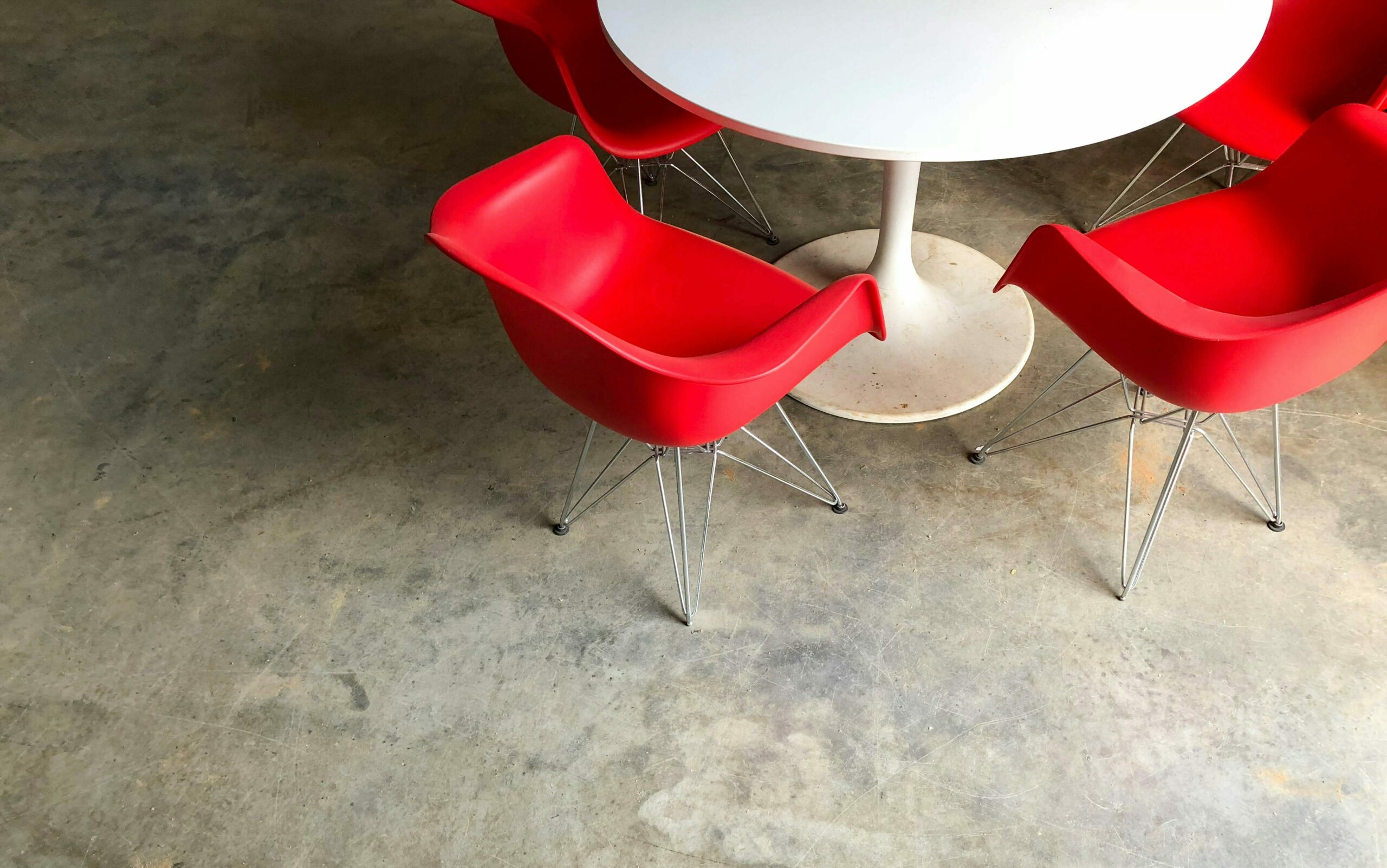 Photo of red chairs around white table. Photo: by No Revisions on Unsplash.