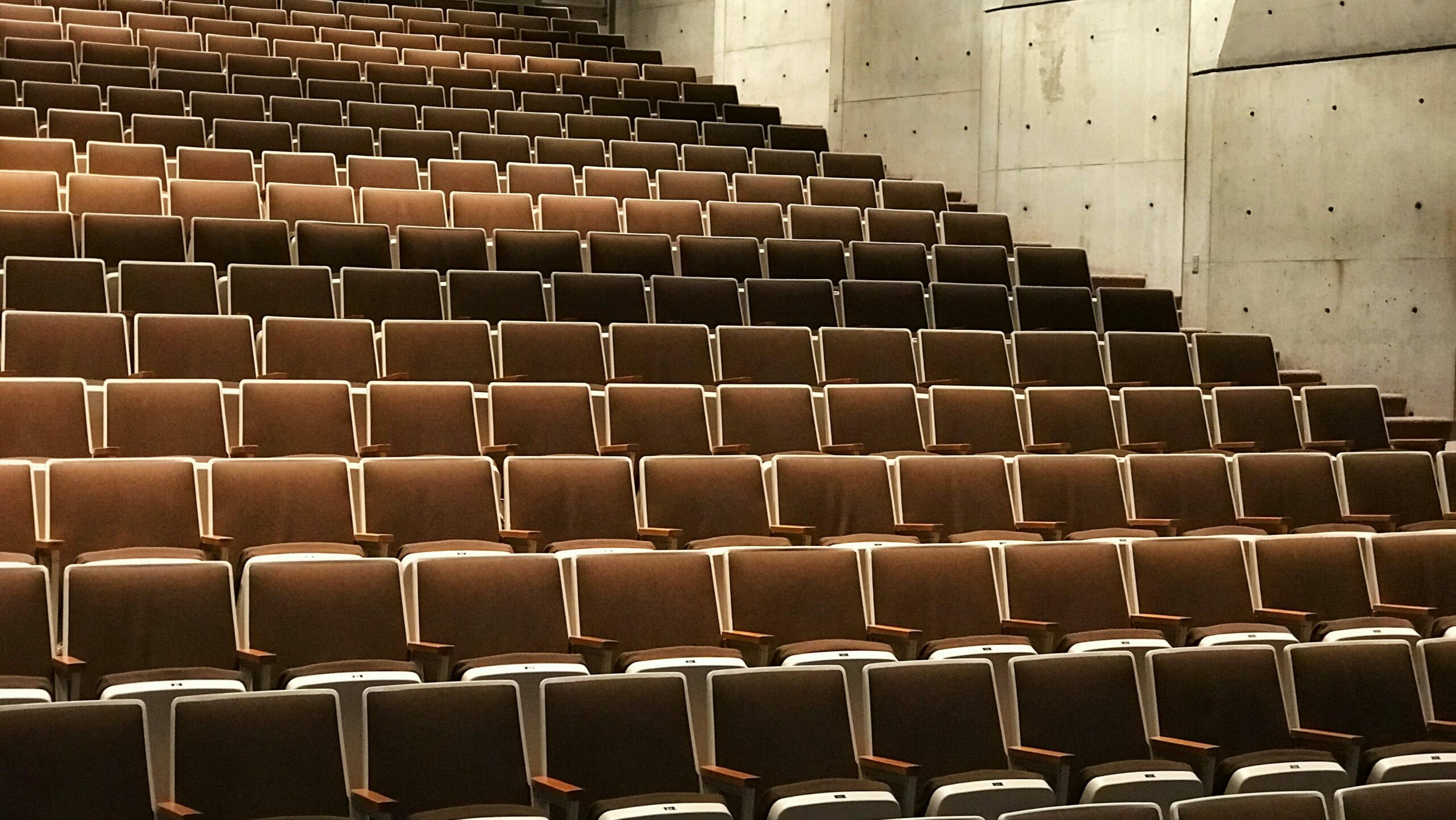 Photo of many brown fabric seats in a lecture hall. Photo: Tyler Callahan on Unsplash.