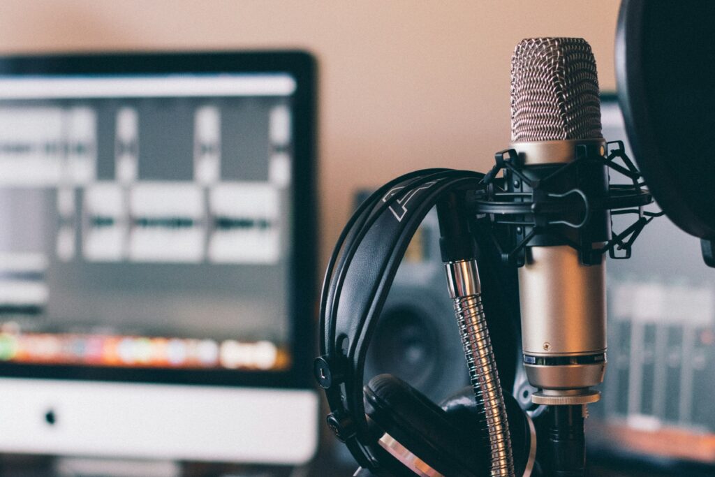 Photo of an up close silver microphone with a black headset hanging off it. Photo: Will Francis on Unsplash.