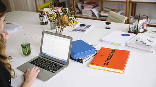 woman at a table with laptop and books