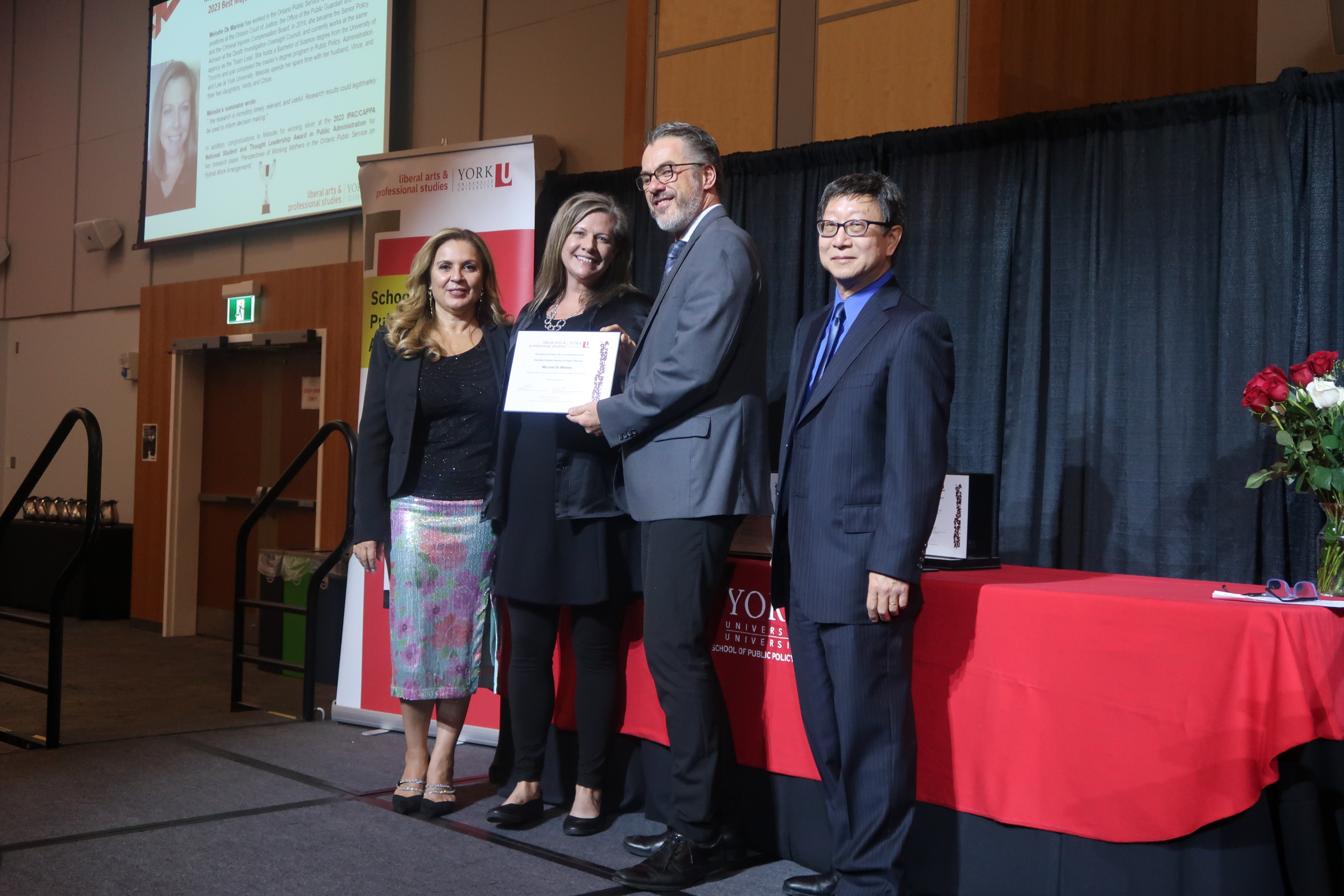 Professor presenting certificates to graduate students on stage 