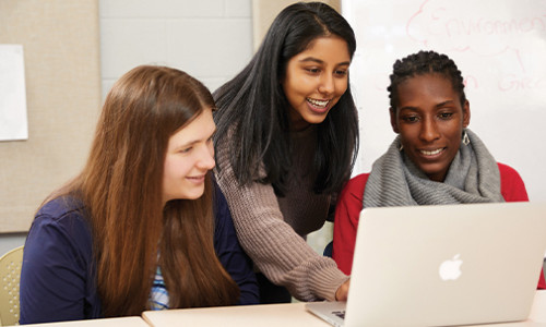 three female students around laptop