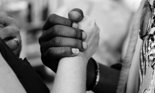 close up of white and black persons clasping hands