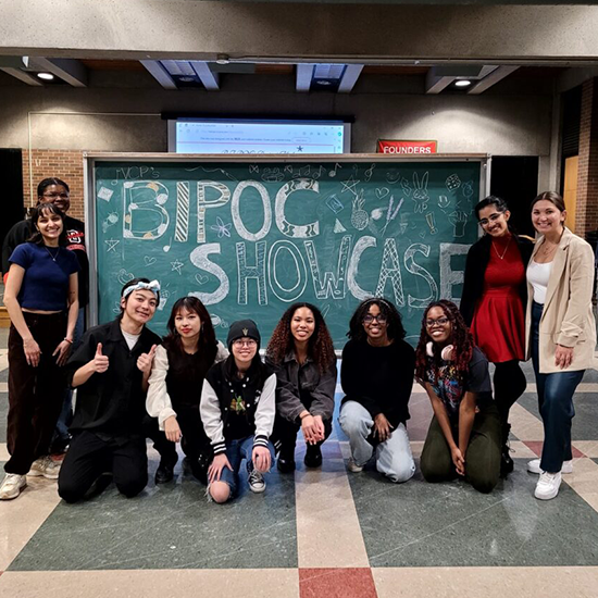 Group of BIPOC Artists posing for a photo with a black board that reads 