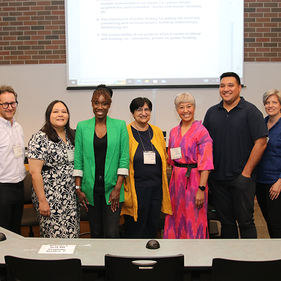 Group of people standing at the front of a lecture room, posing for a photo.