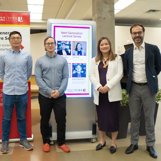 Four people standing in front of a digital kiosk with their pictures on it.