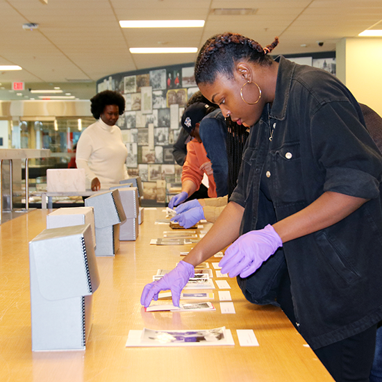 Attendees participating in a archival workshop, handling old photographs while wearing gloves.