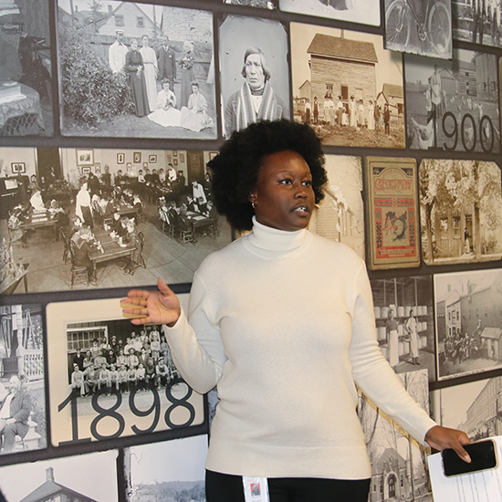 Melissa Nelson speaking while standing infront of a display of archives.