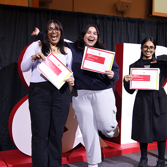 Three students posing on stage with their certificate of completion from the Advancing YU program.