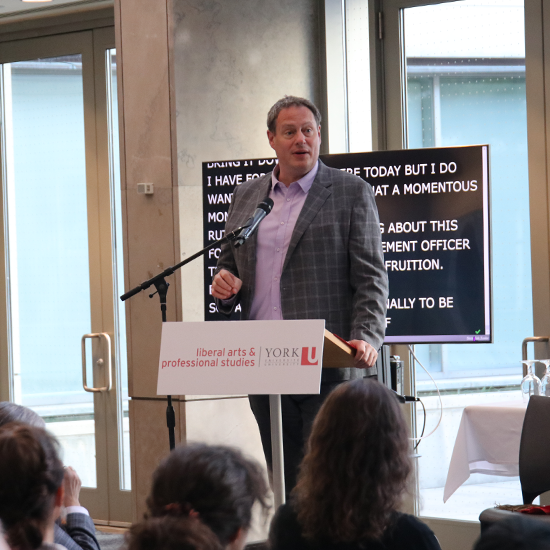 Dean J.J. McMurtry standing behind a podium speaking into a mic.