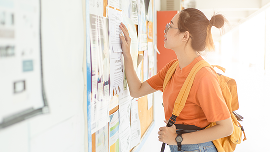 young university woman looking at the post board