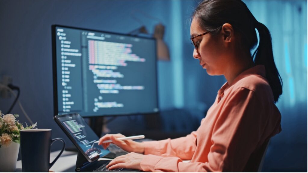 Student in front of a tablet and computer working with codes