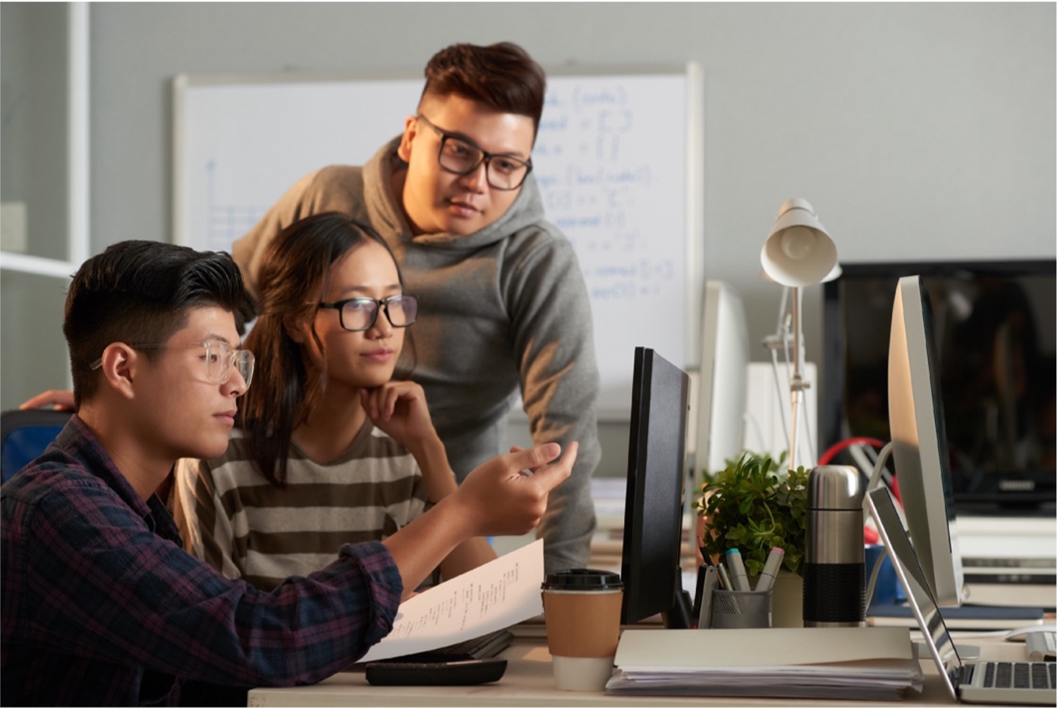 Three students around a computer