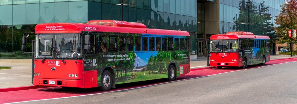 Two York electric shuttle busses in a row at bus stop on Keele Campus