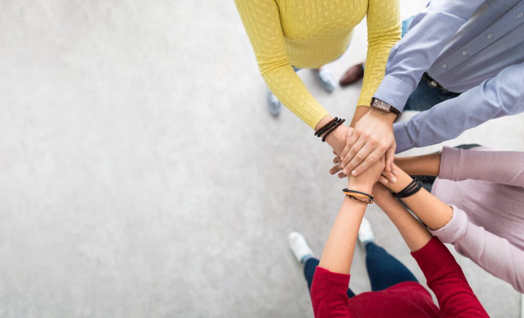 A circle of people with hands outstretched to centre.