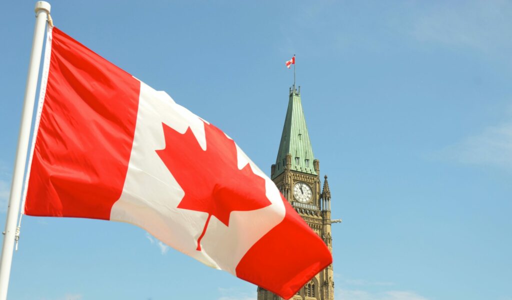 Canadian Flag waves in the wind in front of Canadian Parliament