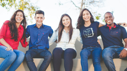 Group of students smiling with arms wrapped around each other