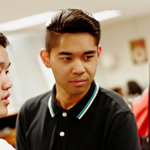 Two students work together on the same computer monitor.