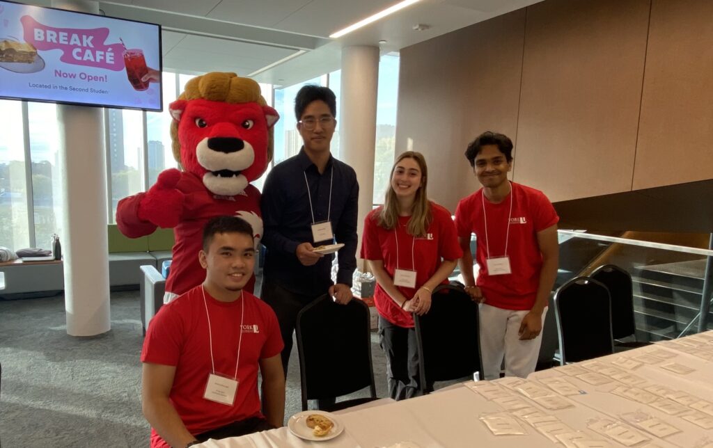 1 woman and 3 men standing with York Mascot 