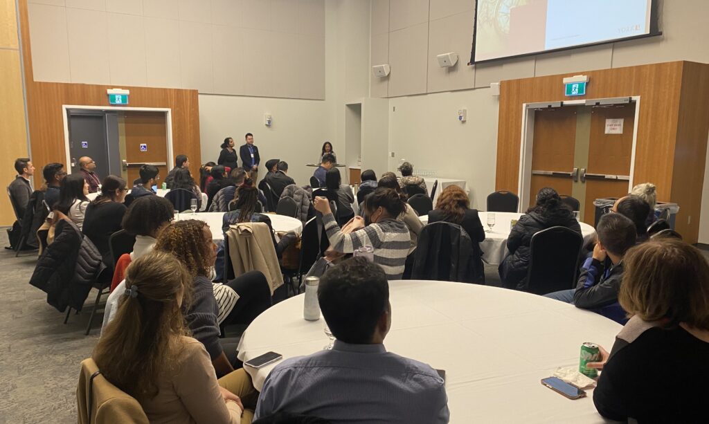 people sitting at round tables watching a presentation 