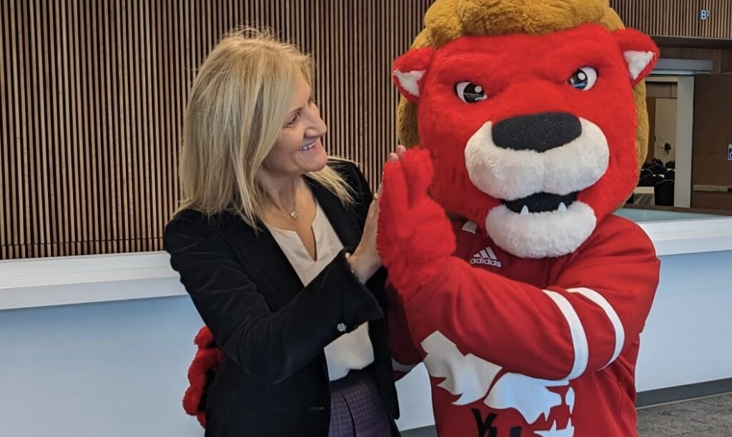 Blonde woman high-fiving York mascot 