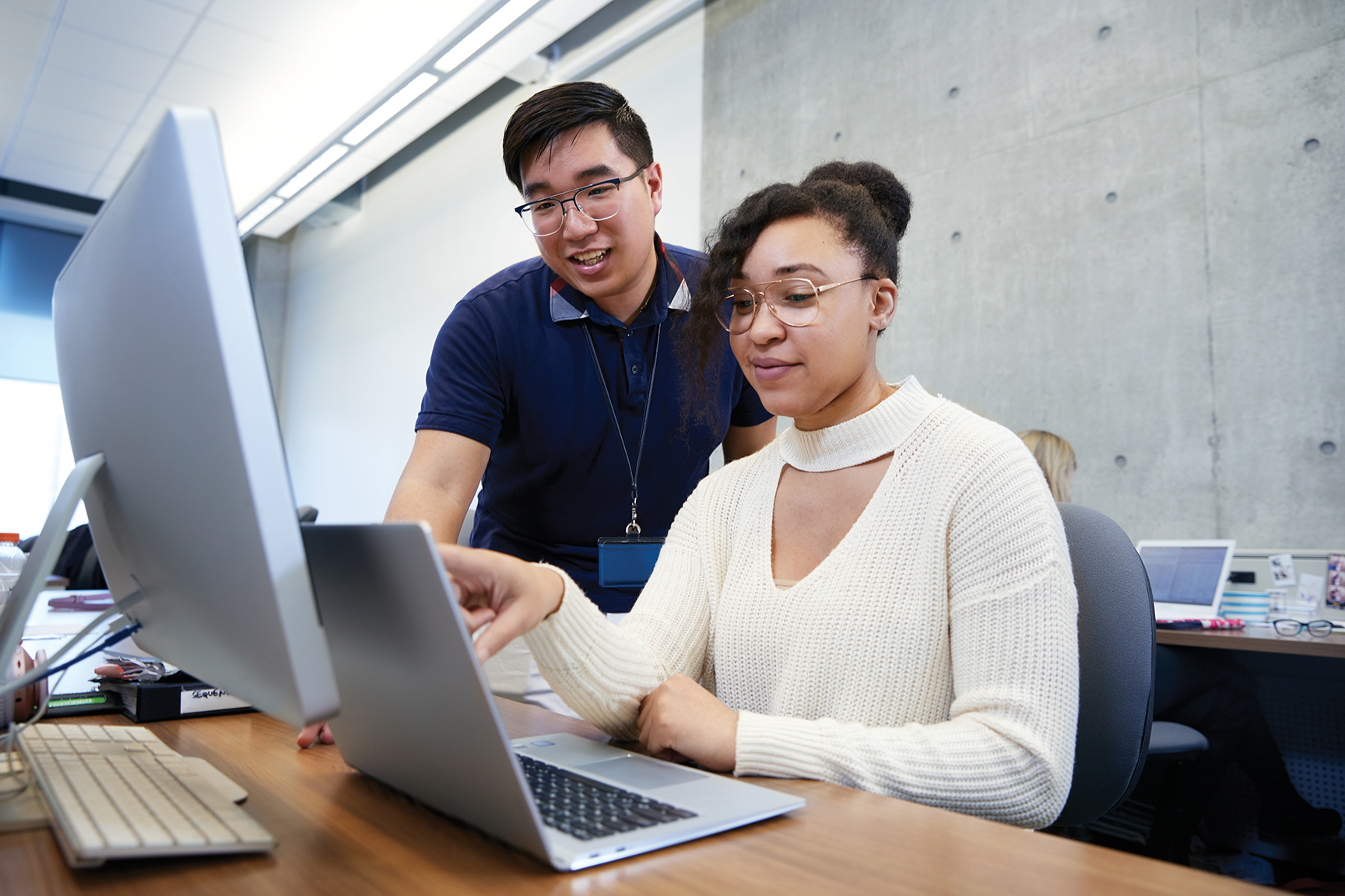 woman and man sitting in front of a laptop and monitor 