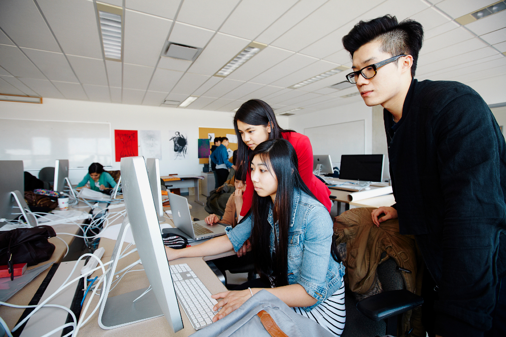 3 people working at a desktop computer 