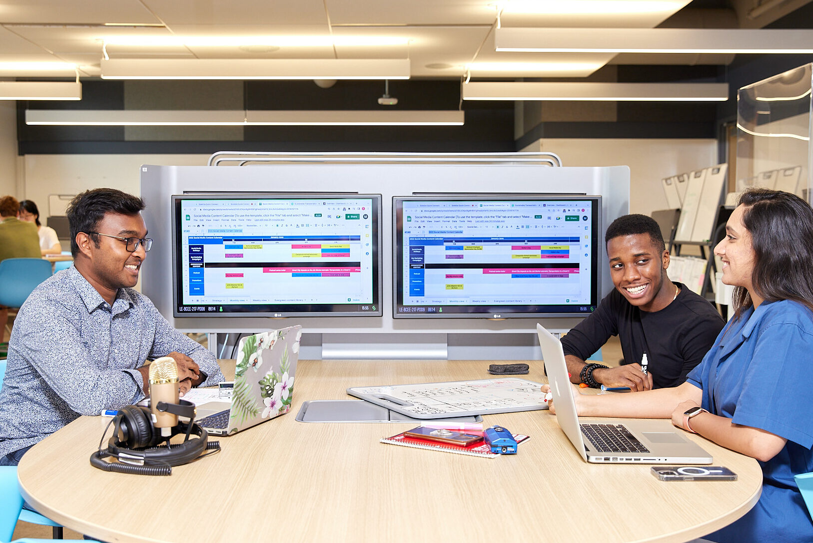 three students working on two laptops and 2 monitors 