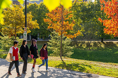 Students walk by campus buildings in Fall