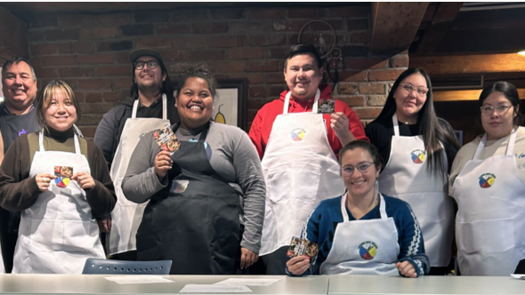 A group of diverse students smiling while wearing cooking aprons