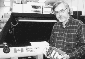 Tom McElroy holds the CPFM instrument next to the pod into which it was placed. The instrument measured gases in the atmosphere.